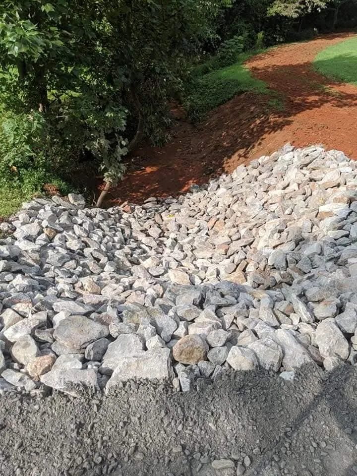 A stone outlet built into a hillside to slow and spread stormwater — Little Acres Grading