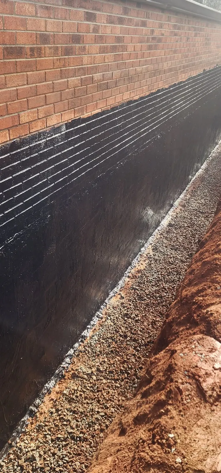 A foundation trench with waterproofing and stone backfill for drainage — Little Acres Grading