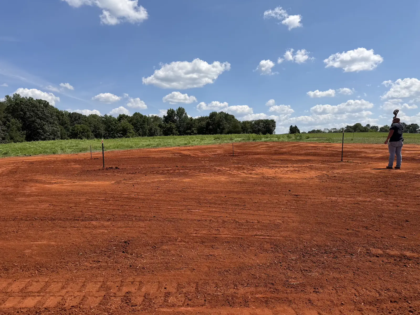 A building pad cut and staked out on open pasture ground — Little Acres Grading