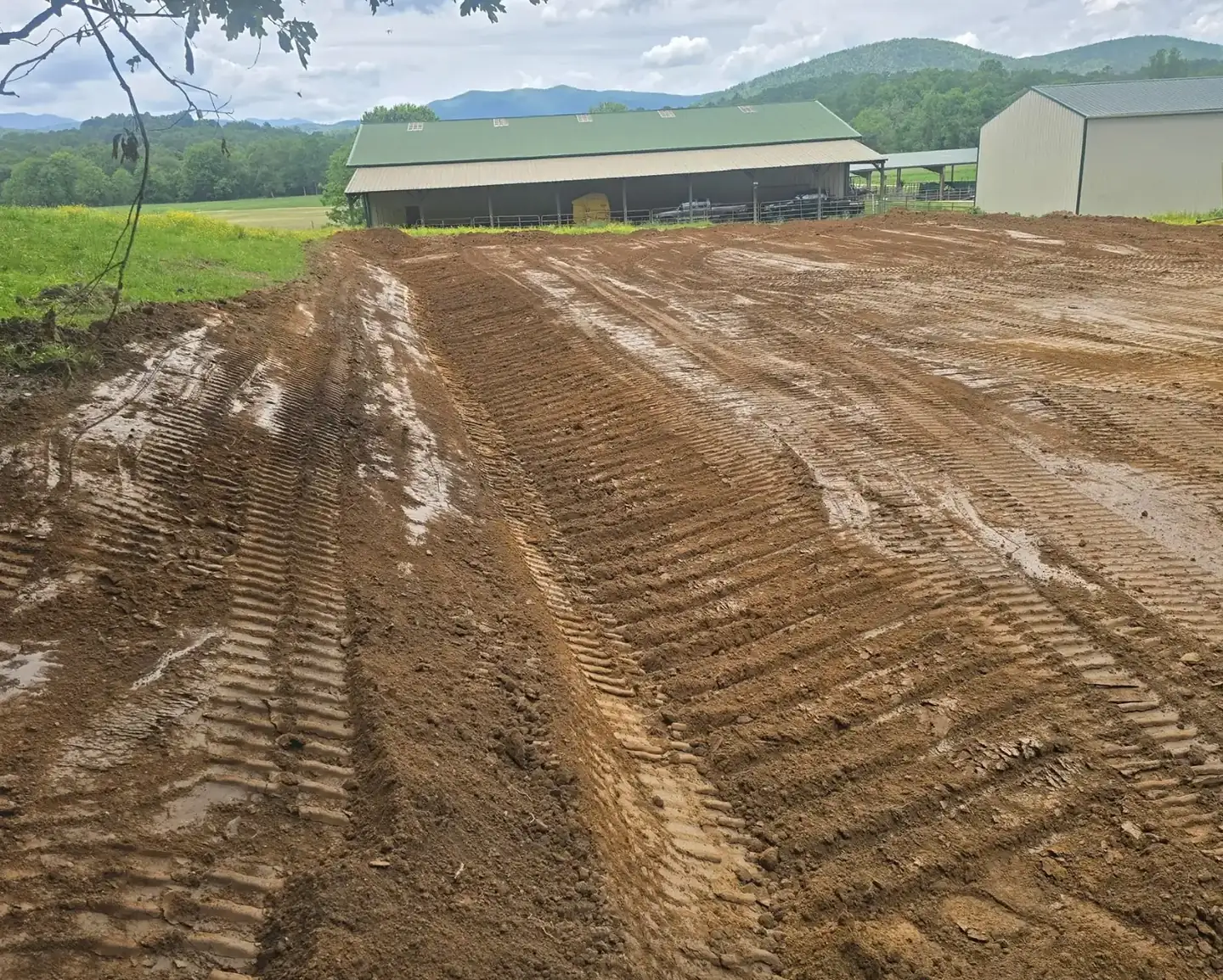A slope cut and graded on a farm with the mountains behind it — Little Acres Grading