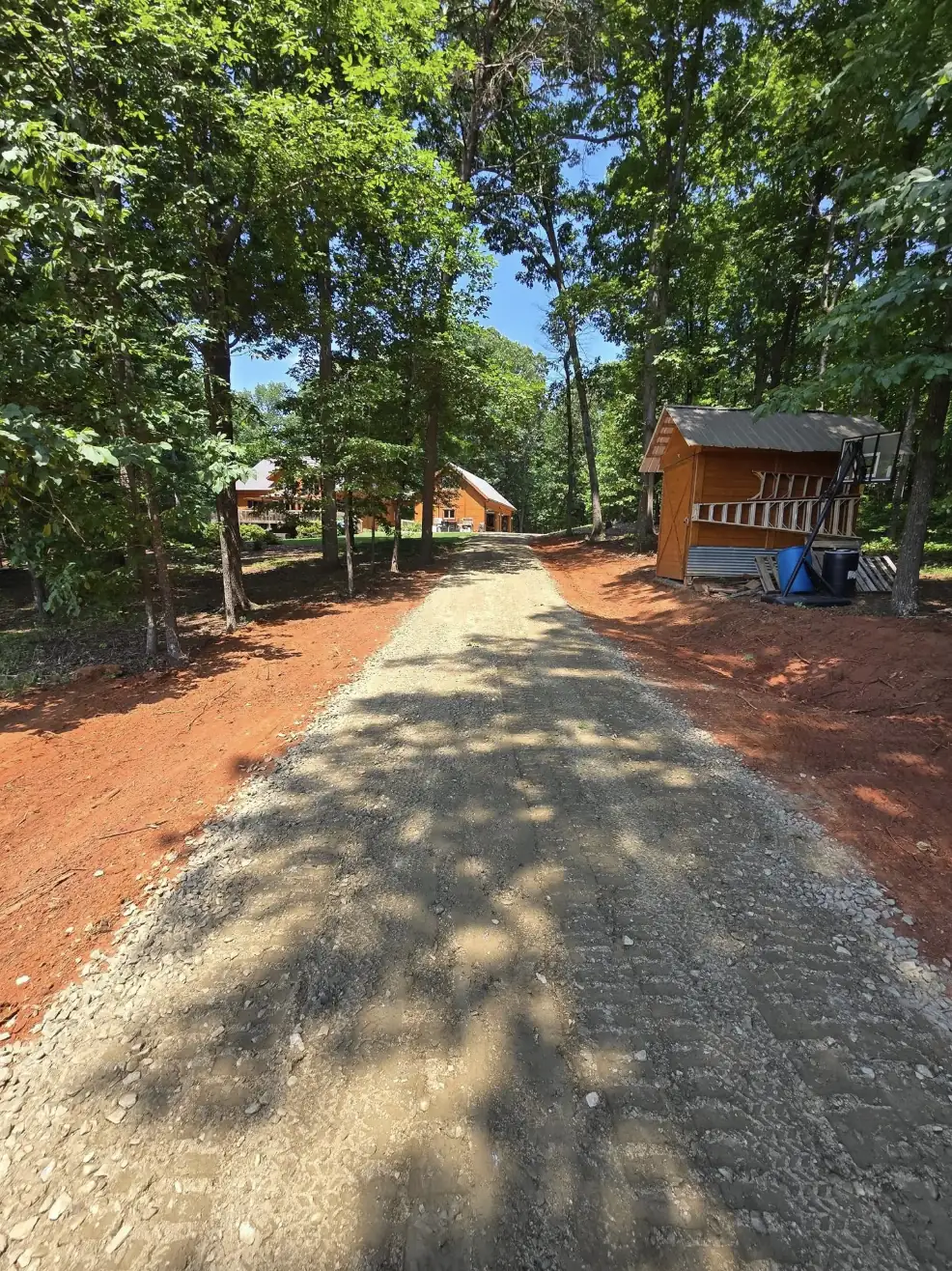 A gravel drive graded up through a wooded lot to a cabin — Little Acres Grading