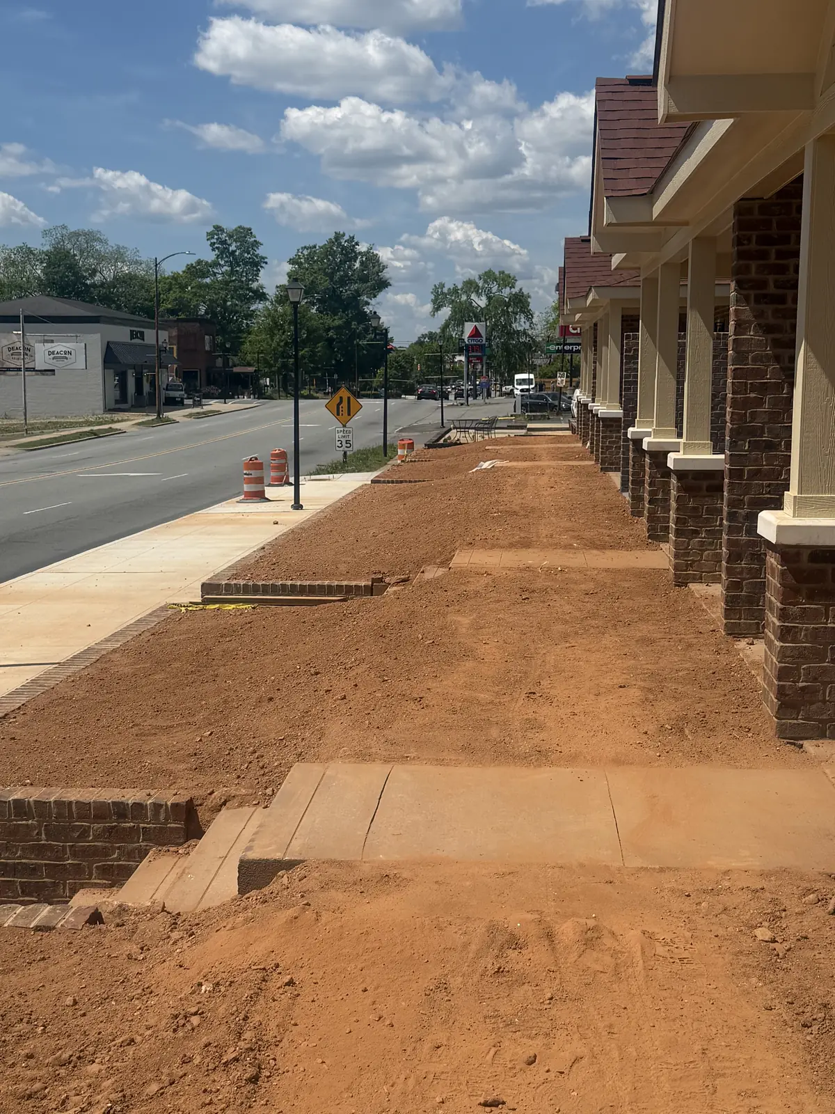 Grade work along a downtown storefront sidewalk ahead of landscaping — Little Acres Grading