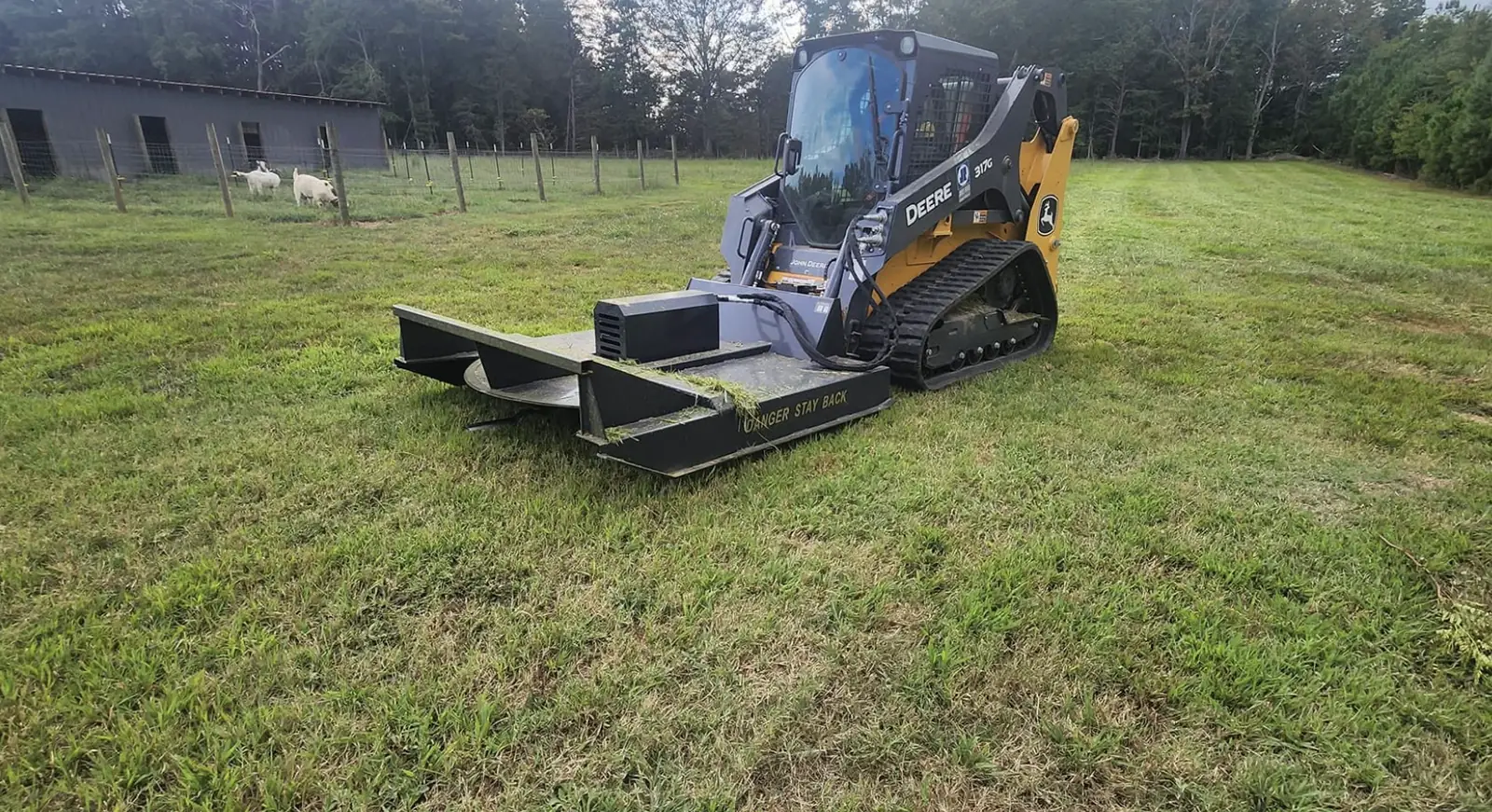 A skid steer with a brush cutter attachment clearing pasture — Little Acres Grading
